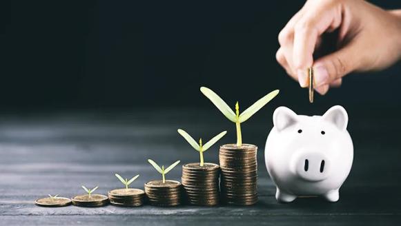 Growing stacks of coins leading to a piggy bank.