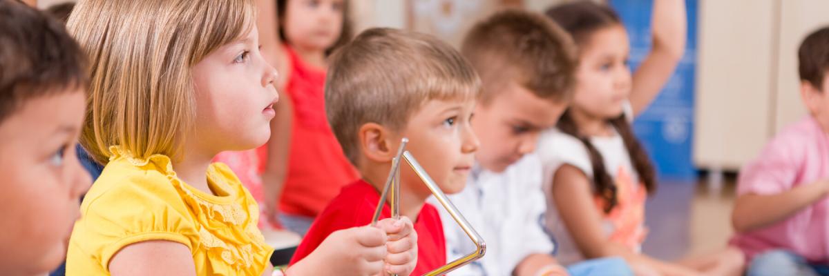 Childs playing musical instruments in classroom.