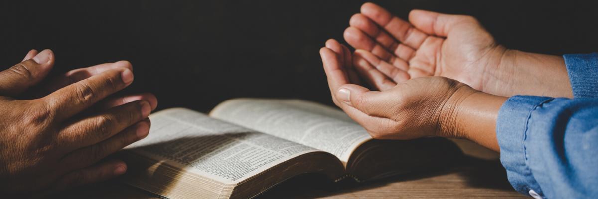 Two people holding their hands open atop a Bible, praying worship believe, devotional for prayer meeting concept